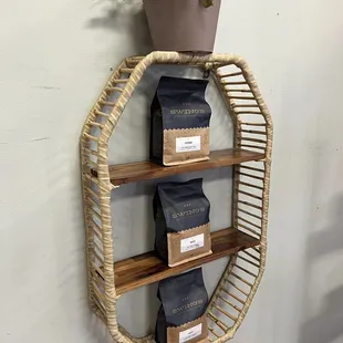 a shelf with coffee bags and a potted plant