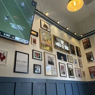a wall of framed photos and a flat screen tv