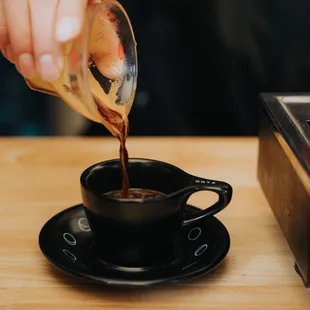 a person pouring coffee into a cup