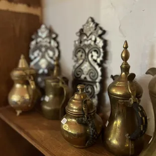 a shelf of brass teapots