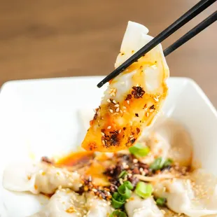 a plate of dumplings with chopsticks