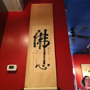 a woman standing in front of a chinese scroll