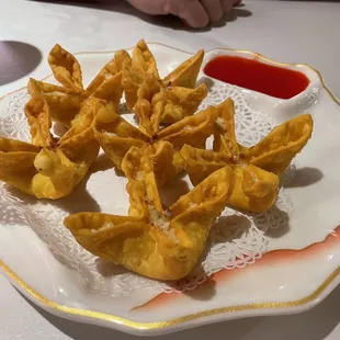 a plate of wontons with dipping sauce