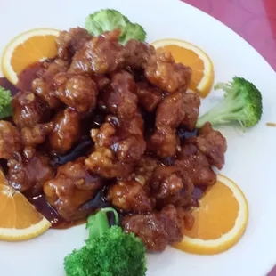 Large General Tso&apos;s Chicken complemented with fresh orange slices and broccoli.