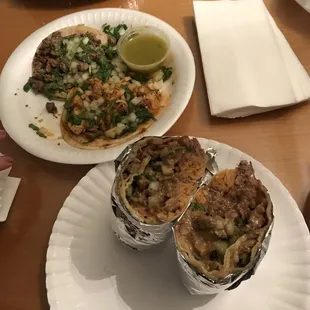 Carne asada burrito cut in half; asada taco and chicken taco in the back