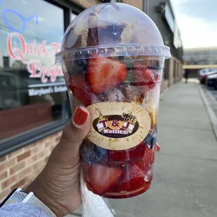 a hand holding a cup of fruit