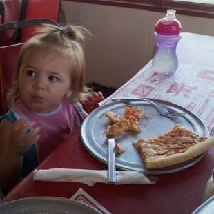 a little girl eating a slice of pizza