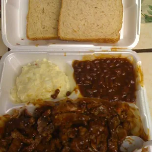 e shows a tray of meat, beans, bread, and mashed potatoes