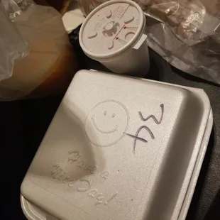 a white takeout container with a smiley face drawn on it