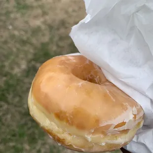 a hand holding a glazed donut
