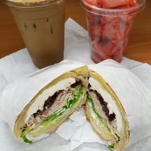 A turkey, cranberry, and cream cheese sandwich on a croissant with watermelon and a Vietnamese iced coffee. YUM!!!