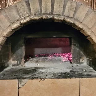 a brick oven with pink flowers in it