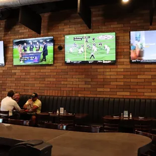 a group of people sitting at a table watching televisions