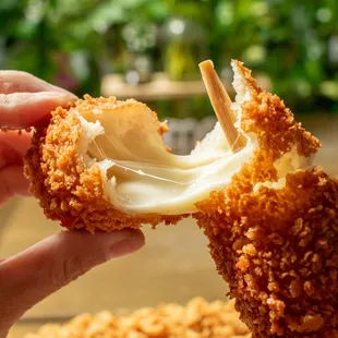 a hand holding a piece of deep fried breaded chicken