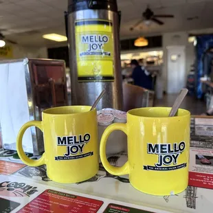 two yellow coffee mugs on a table