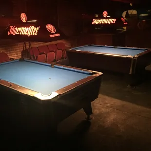 two pool tables in a dimly lit room