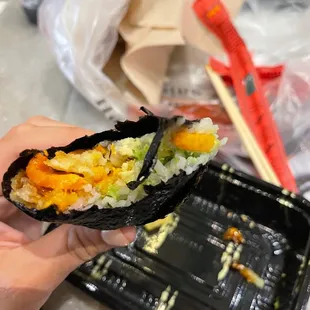 a hand holding a piece of sushi