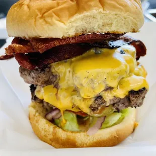 a hamburger with bacon, cheese, and lettuce