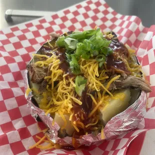 a hot dog wrapped in foil and topped with cheese