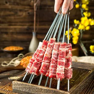 person holding a skewer of meat