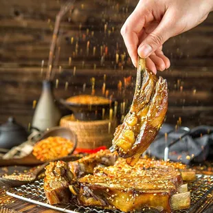 person sprinkling sauce onto a piece of meat