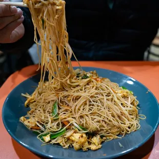 a plate of noodles with chopsticks