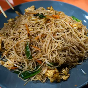 a plate of noodles with chopsticks