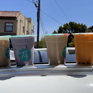 four cups of iced coffee on top of a car