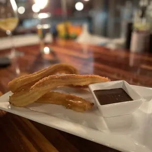 a plate of churros and dipping sauce