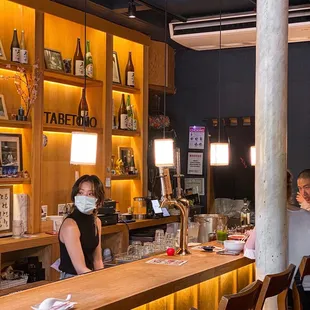 a woman wearing a face mask behind a bar