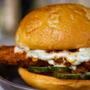 Buffalo Chicken Sandwich | breaded chicken tenders tossed in buffalo sauce, housemade pickles, grilled bun, bleu cheese aioli (GF available)