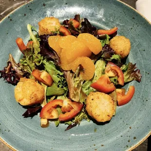 a plate of salad with oranges and croutons