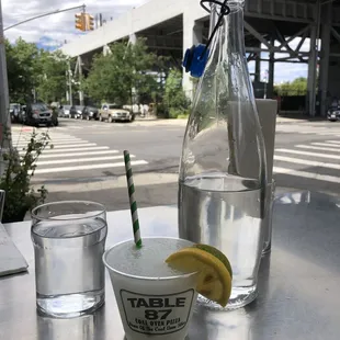 a glass of water, a lemon wedge, and a bottle of water
