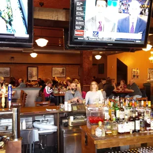 people sitting at a bar watching tvs