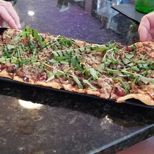 a person cutting a pizza on a cutting board