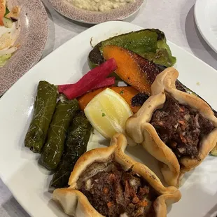 Sampler with grilled veggies, stuffed grape leaves, meat pies, and baba ghanoush