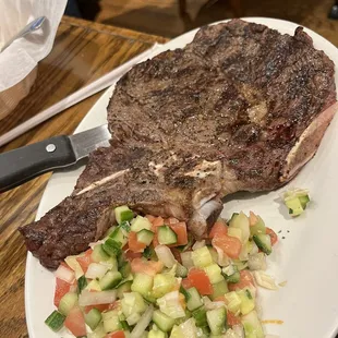 a large steak and a salad on a white plate