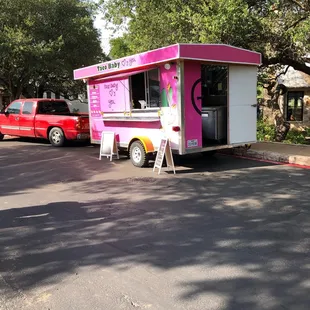 a pink food truck parked in a parking lot