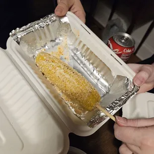 a person holding a tray of corn