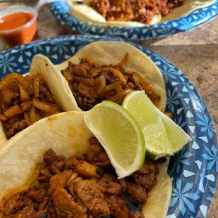 two plates of tacos with lime wedges