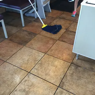 No employees around mop left and a wet floor.