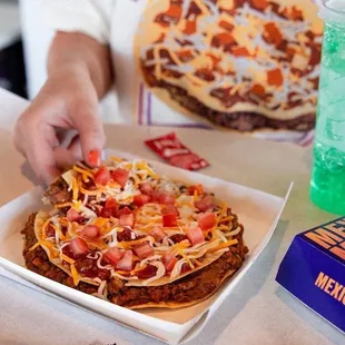 a person putting toppings on a pizza