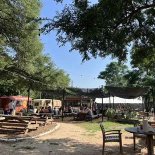 a group of people sitting at tables under a tree
