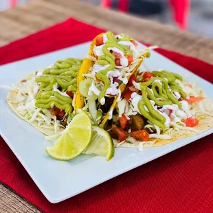 a plate of tacos with lime wedges
