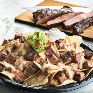 a plate of nachos with steak and guacamole