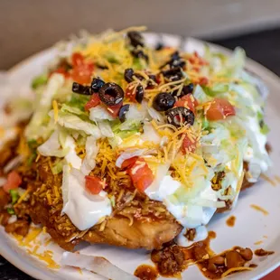 a plate of taco topped with lettuce and tomatoes