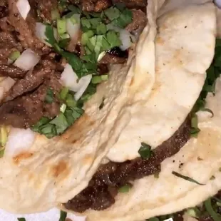 two tacos on a plate with lime wedges