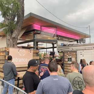 a crowd of people standing outside of a taco stand