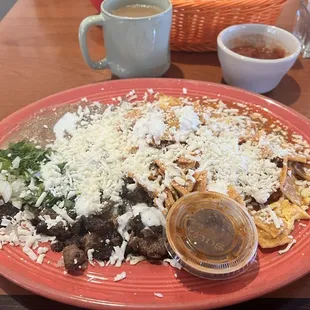 Ultimate chilaquiles with carne asada, eggs, tortillas chips, cheese, and salsa.