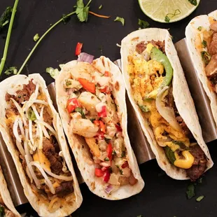 a row of tacos with different toppings